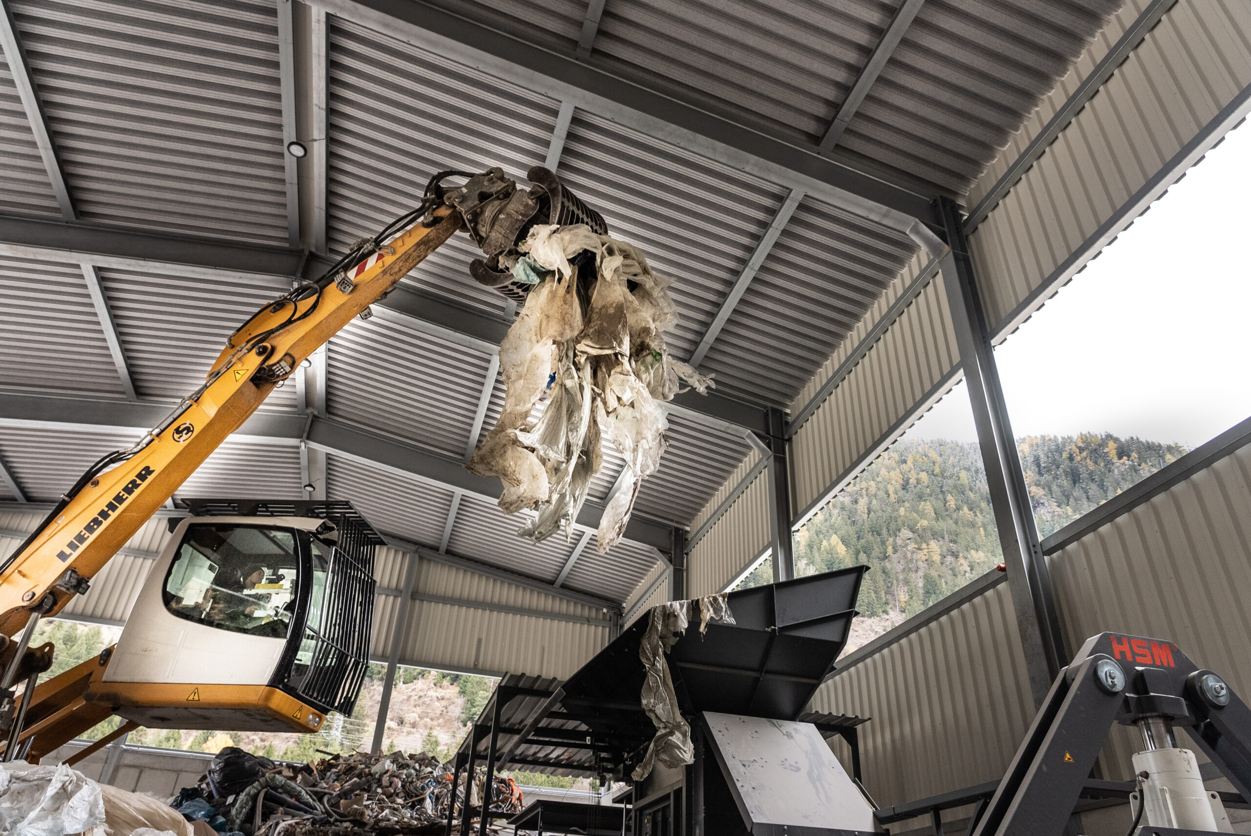 Bagger befördert Kunststoffmüll in eine Kanalpresse